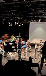 Konzert „Different Cities“ in der Blackbox der HKB/Foto: Julius von Lorentz Musizierende im Kreis vor Aufnahmetechnik in einem schwarzen Raum