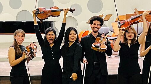 GRuppenbild Streicherinnen und Streicher vor der Bühne des Konzertsaals