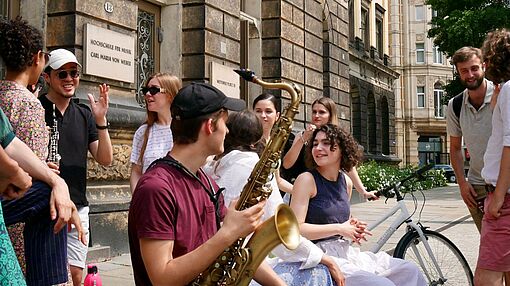 Studierende treffen sich mit Instrumenten vor Musikhochschule Dresden