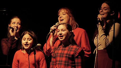 Studentinnen singen mit zwei Schülerinnen