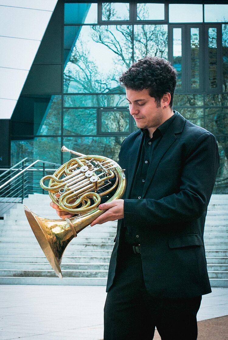 Eduard Cortez mit Horn vor dem Konzertsaal