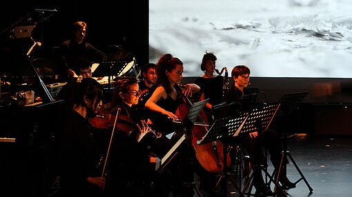 Kammerorchester spielt vor bewegter Leinwand