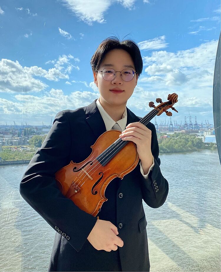 Langyu Qin mit Violine, im Hintergrund Wasser und eine Stadt, zum Aktuelles-Beitrag