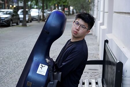 WenTeng Chang mit Cello auf Sitzbank