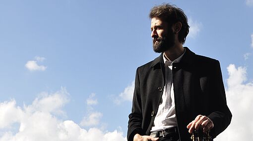 Ozan Coskun mit Gitarre auf einer Balustrade