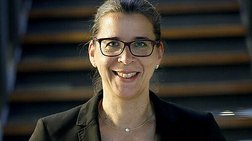 Porträt von Dr. Claudia Schlüter vor Treppe