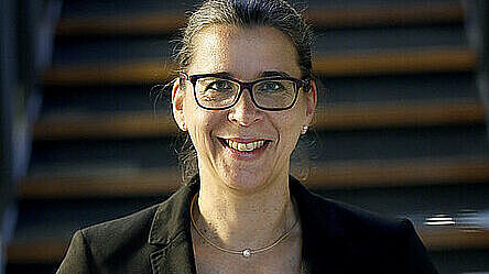 Porträt von Dr. Claudia Schlüter vor Treppe