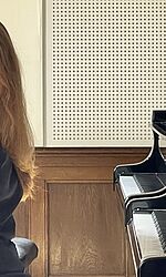 Sophia Kratschkowskaja sitzt am Klavier und lächelt in die Kamera